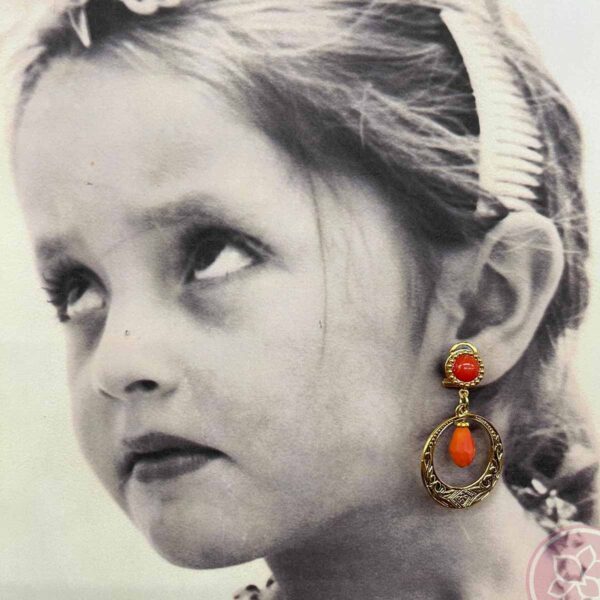 Pendientes para niña compuesto de aro dorado y lágrima de color coral, de la casa sevillana Carvajal. Complementos únicos realizados artesanalmente, perfectos tanto para eventos especiales como para flamenca.